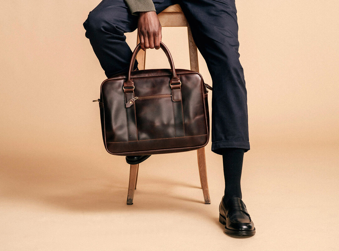 Ein Mann, der mit einer Tasche auf einem Barstuhl sitzt.