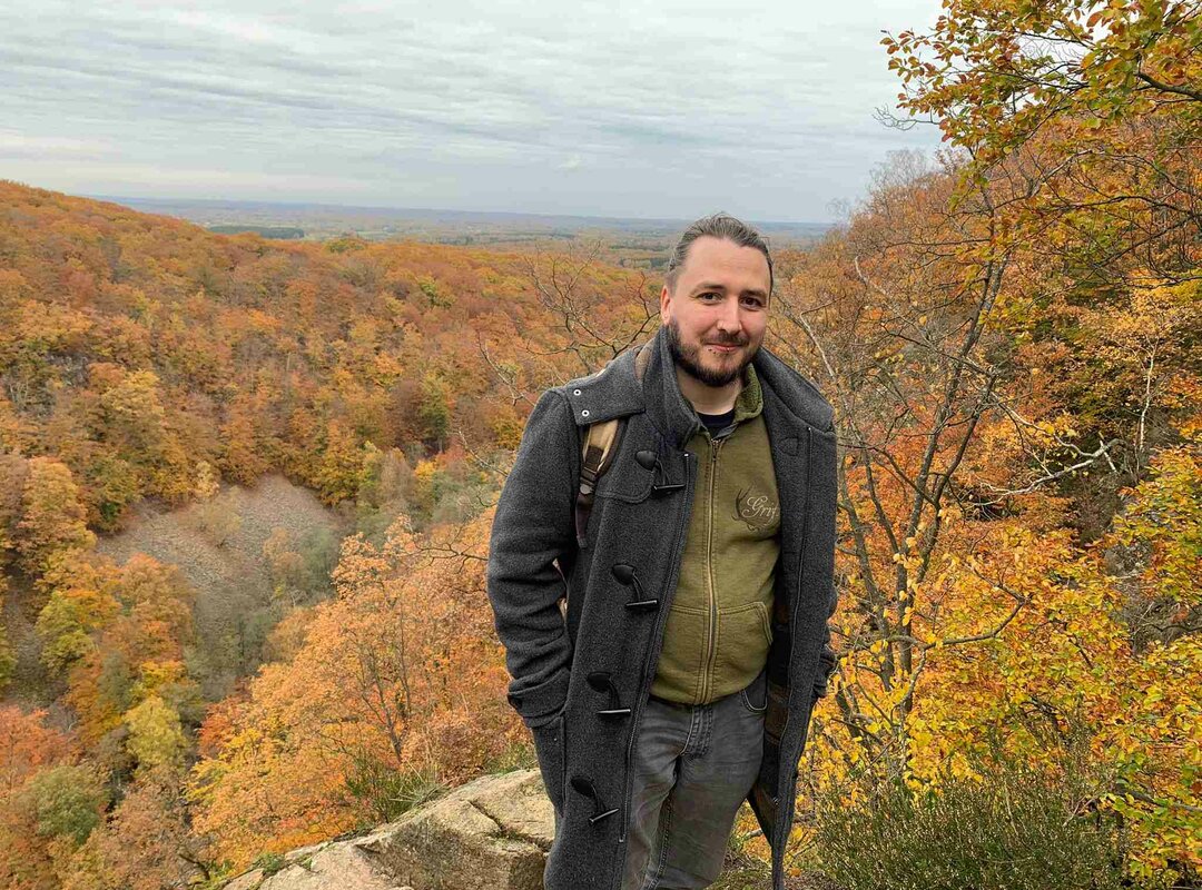 Der Rieck Azubi Peter Balthasar posing für ein Foto vor einem Wald.