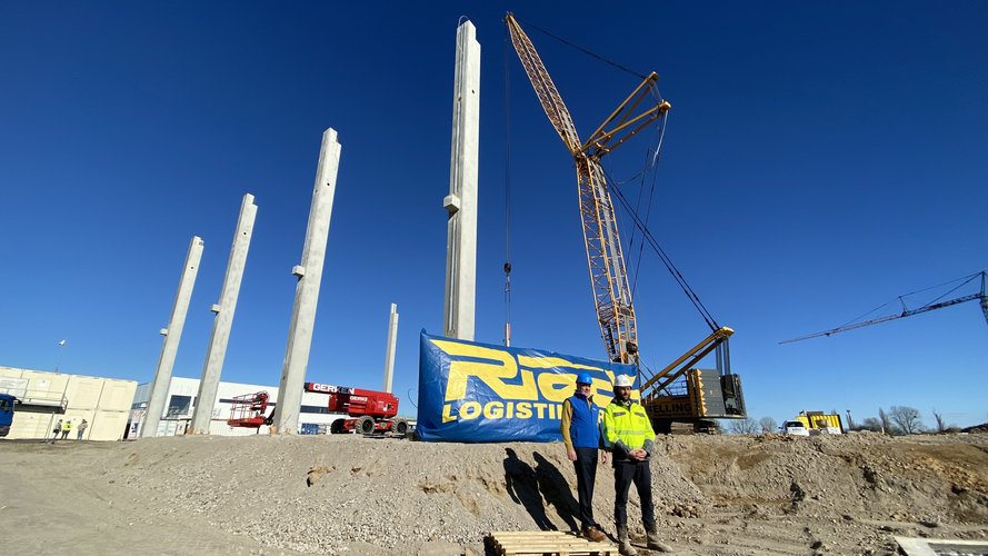 2 Bauarbeiter vor dem Rieck Logo weiter weg.