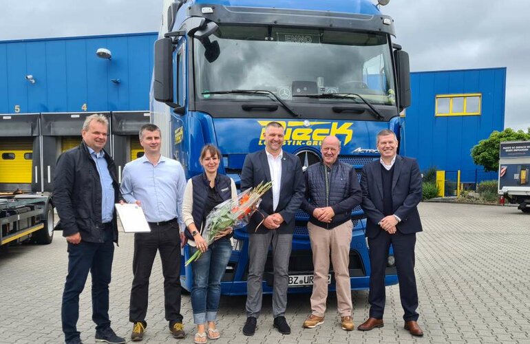 Eine Gruppe von mitarbeitern mit einem Blumenstrauß zum Jubiläum.