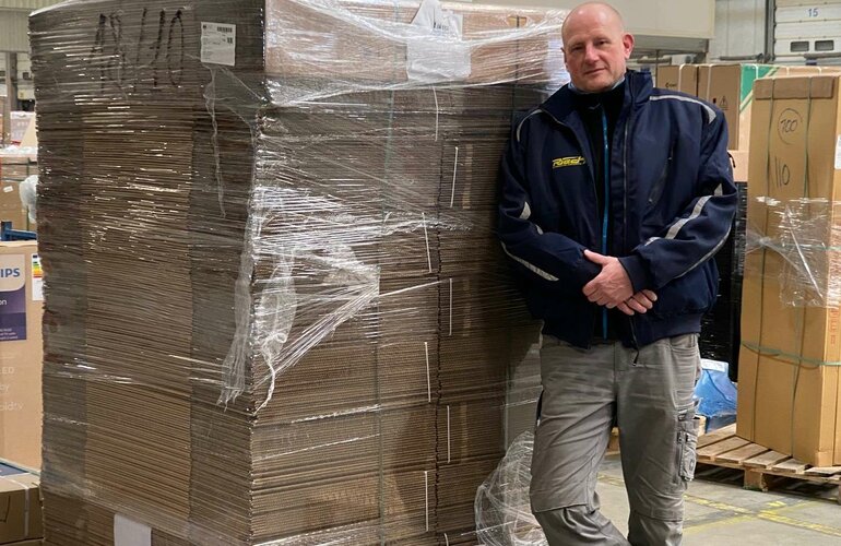 Thomas Behm vor einer eingepackten Palette.