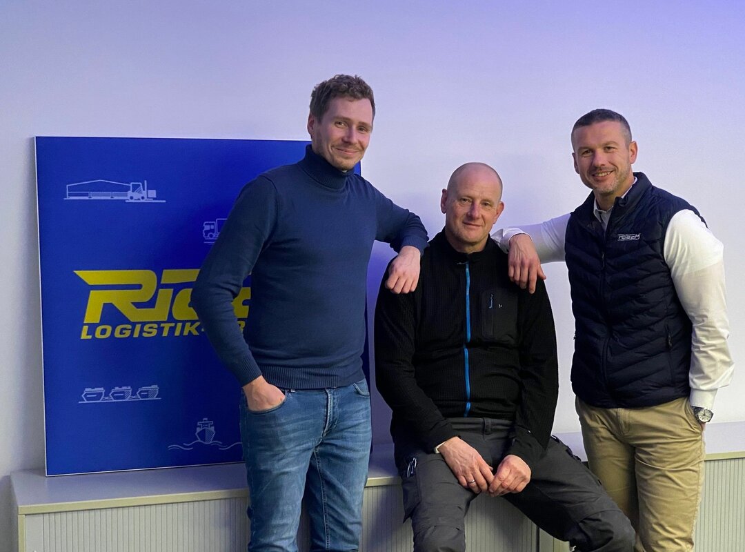 3 Männer vor einer Wand mit dem Rieck-Logo.