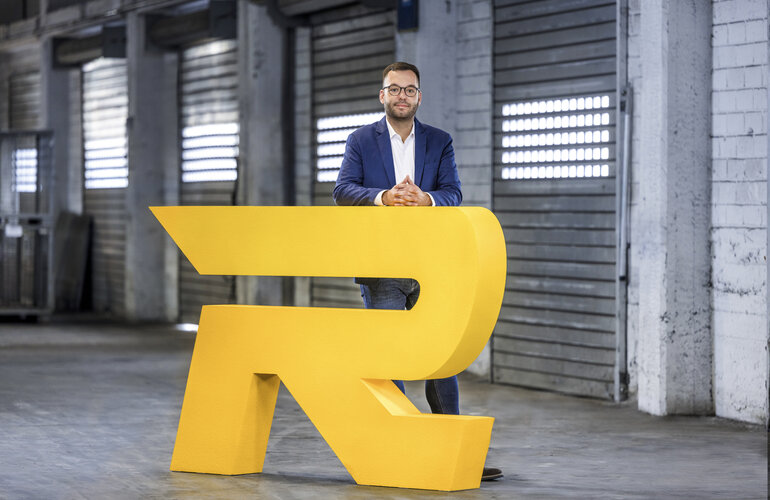 Lennard Ratzer vor dem Rieck Logo.