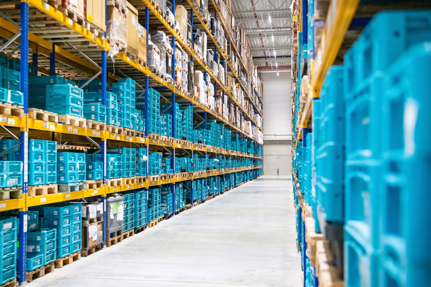 Großes Lager für Lagerlogistik mit hohen Regalen und blauen Kunststoffboxen.