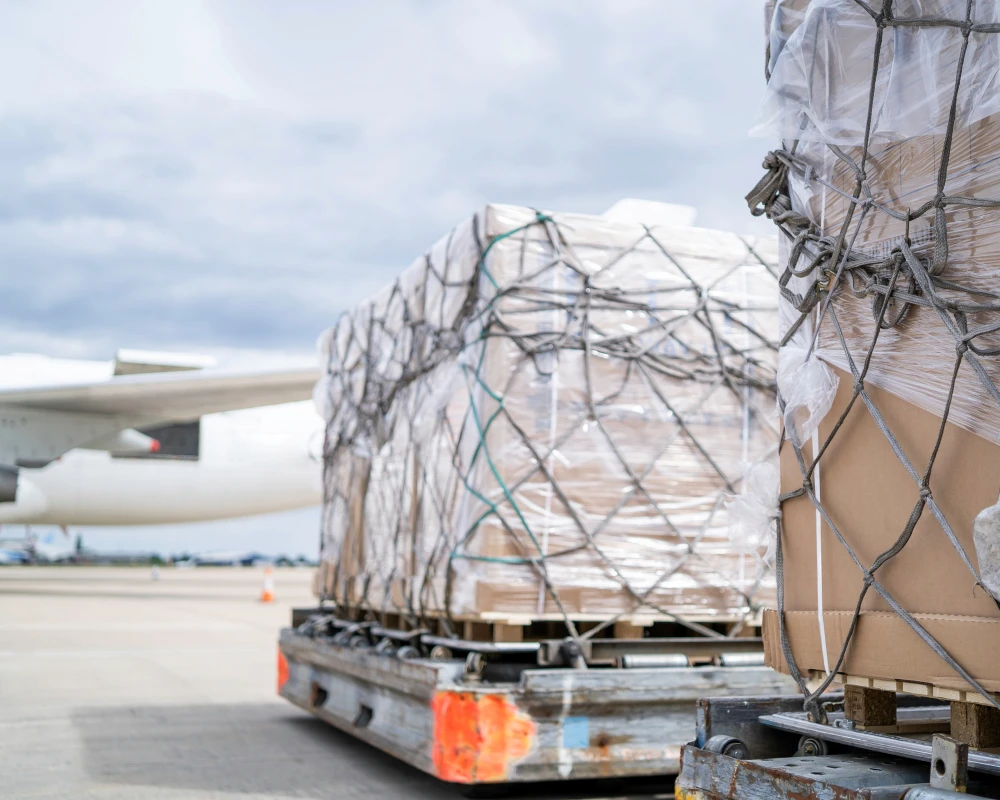 Paletten mit verpackten Waren auf einem Flughafenrollfeld, bereit für den Luftfracht-Transport.